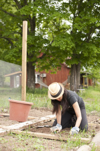 one of our volunteers weeding in the organic garden with a cool hat on