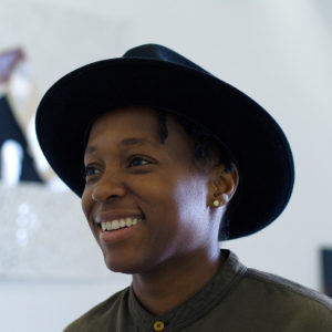 headshot of Ayanah Moor wearing a hat and smiling
